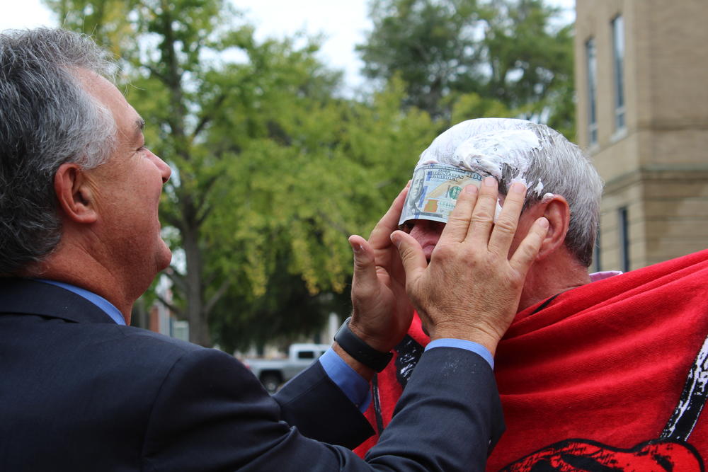 Mayor Gillespie sticking money to Sheriff Sedinger's forehead